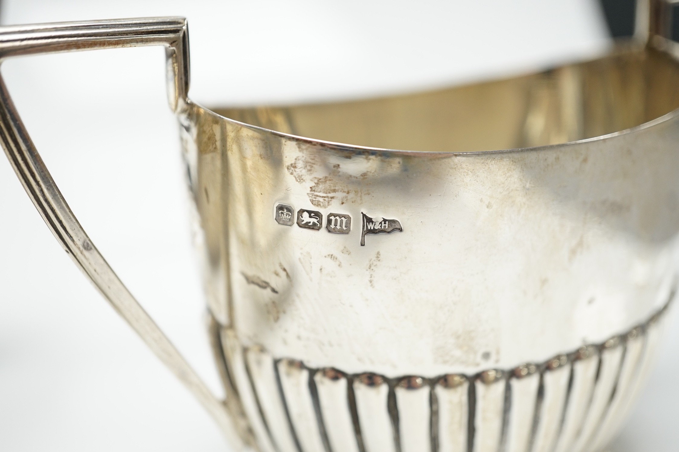 A matched early 20th century silver bachelor's three piece tea set, tea pot, James Dixon & Sons, Sheffield, 1920, cream and sugar, Walker & Hall, Sheffield, 1904, gross weight 14oz.
